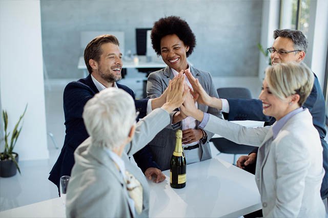 successful business team gathering hands unity while celebrating office